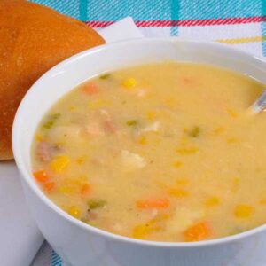 a bowl of homemade clam chowder served with a roll